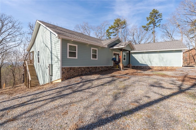 ranch-style house with gravel driveway and stone siding