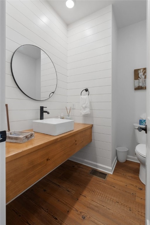 bathroom featuring visible vents, toilet, vanity, wood finished floors, and baseboards