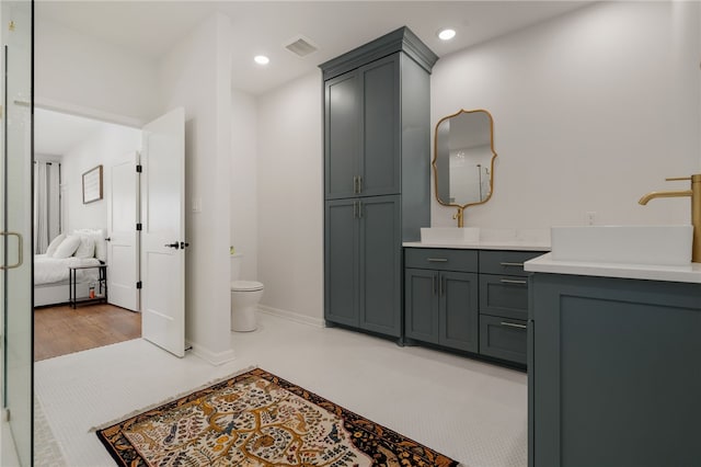 ensuite bathroom featuring visible vents, baseboards, toilet, vanity, and recessed lighting