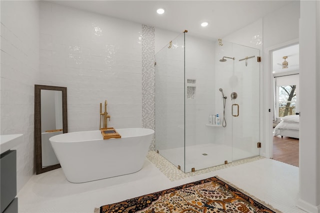 ensuite bathroom with tile walls, a soaking tub, connected bathroom, a shower stall, and tile patterned floors