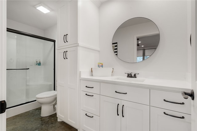 bathroom featuring toilet, a shower stall, and vanity