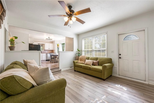 living room with light wood-style flooring, baseboards, ceiling fan, and a textured ceiling