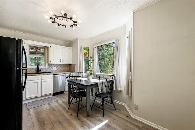 kitchen with light wood-type flooring, freestanding refrigerator, a wealth of natural light, and stainless steel dishwasher