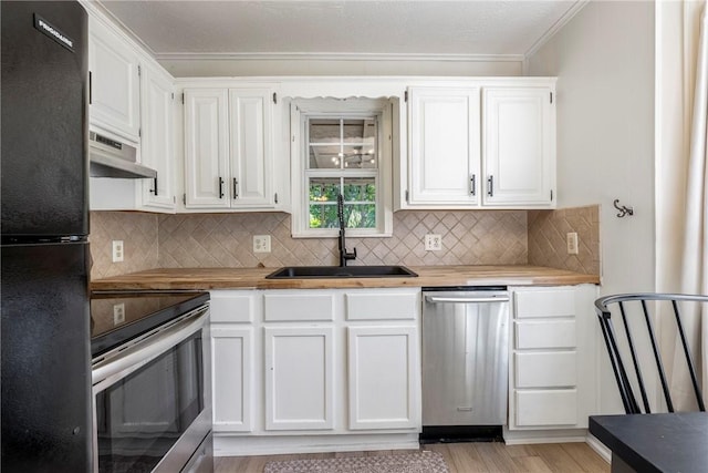 kitchen with a sink, white cabinets, appliances with stainless steel finishes, range hood, and light wood finished floors