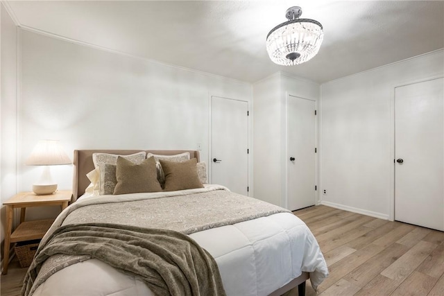 bedroom with light wood finished floors, ornamental molding, and a chandelier