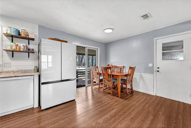 dining room featuring a wainscoted wall, visible vents, and wood finished floors