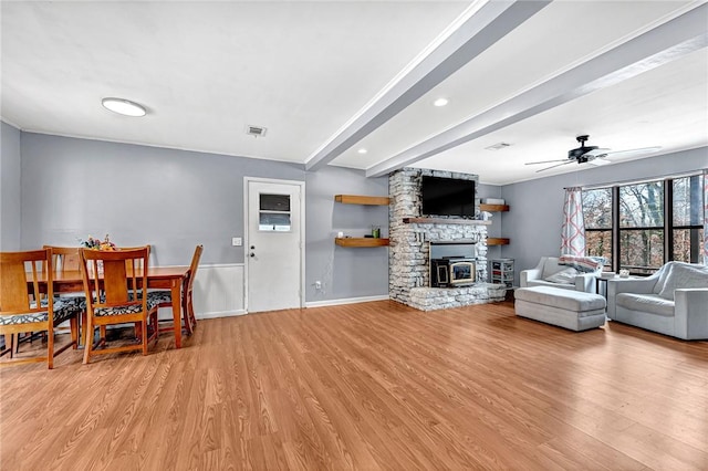 living room featuring light wood-style floors, baseboards, visible vents, and beamed ceiling