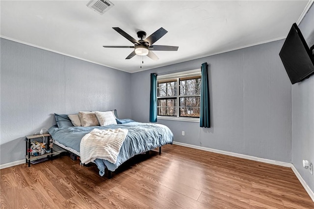 bedroom featuring baseboards, visible vents, wood finished floors, and ornamental molding