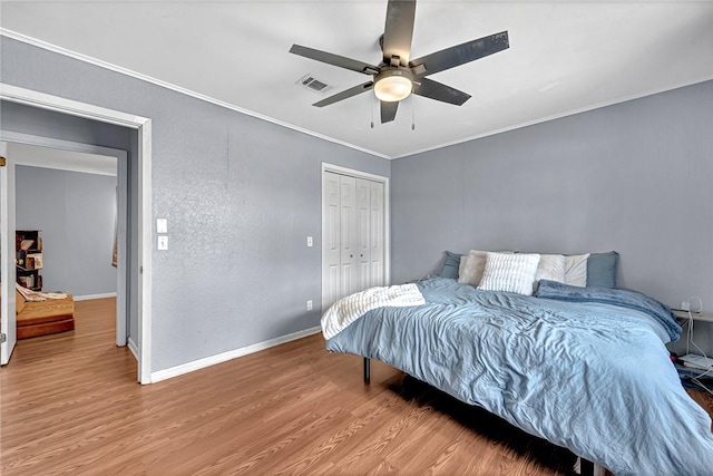 bedroom with ornamental molding, wood finished floors, visible vents, and baseboards