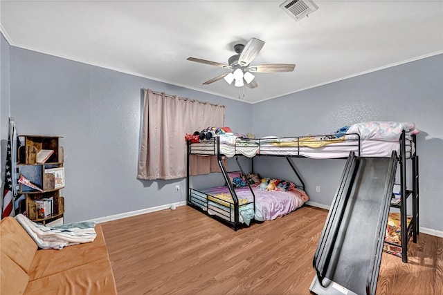 bedroom with ornamental molding, wood finished floors, visible vents, and baseboards