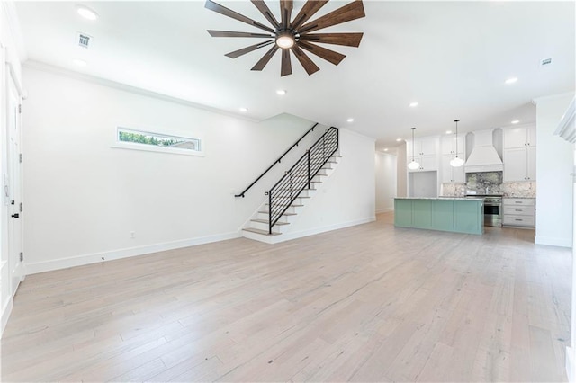 unfurnished living room with stairs, light wood finished floors, baseboards, and recessed lighting