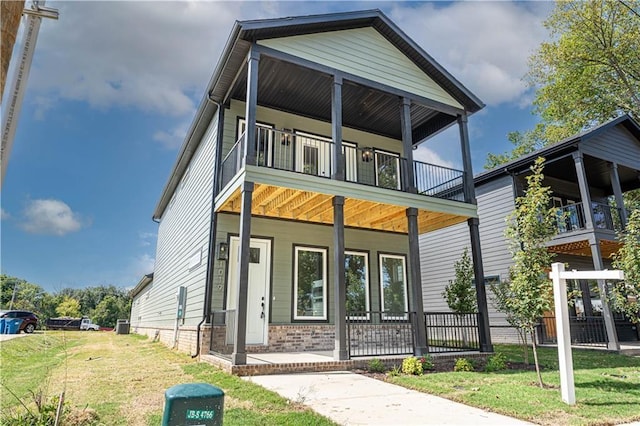 view of front of home featuring a porch, brick siding, a balcony, and a front lawn