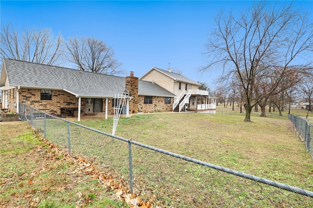 back of house with a fenced backyard, a shingled roof, brick siding, a lawn, and a patio area