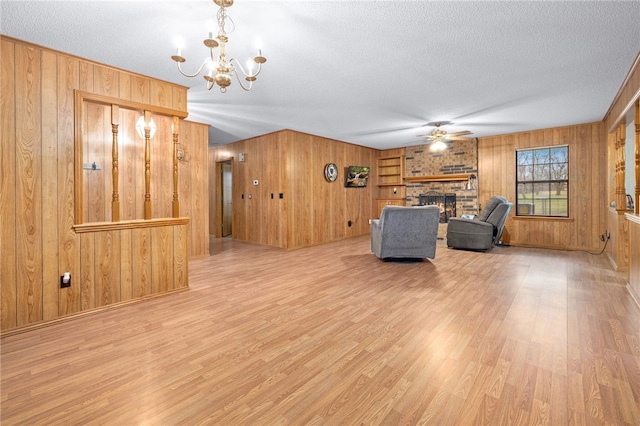 unfurnished living room featuring a fireplace, light wood-style flooring, a textured ceiling, and ceiling fan with notable chandelier