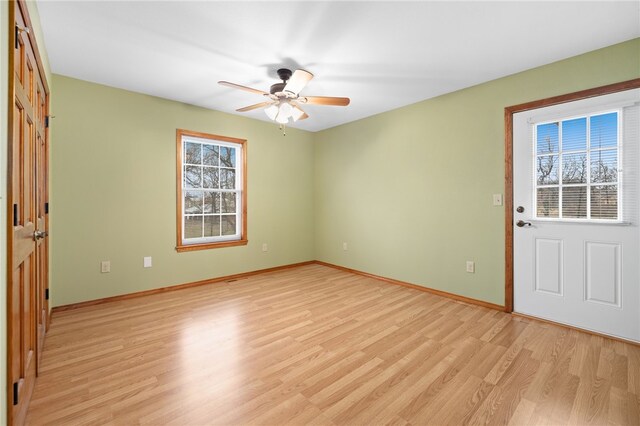 spare room with ceiling fan, light wood-style flooring, and baseboards