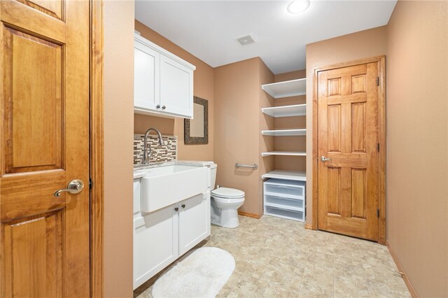 bathroom with visible vents, decorative backsplash, toilet, vanity, and baseboards