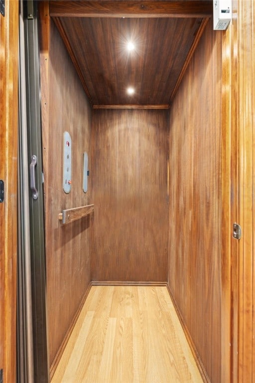 interior details with elevator, wooden ceiling, wood walls, and wood finished floors