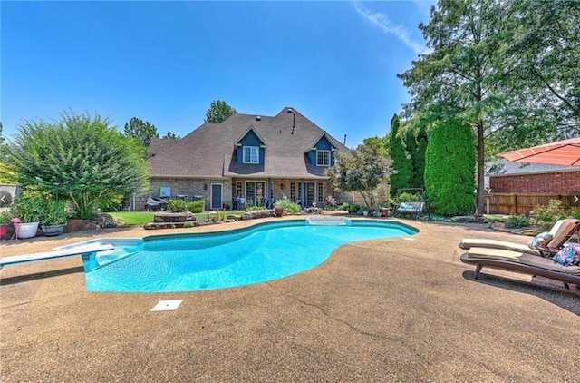 outdoor pool featuring a diving board, a patio, and fence