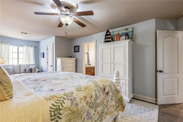 bedroom featuring baseboards, visible vents, ceiling fan, wood finished floors, and ensuite bathroom