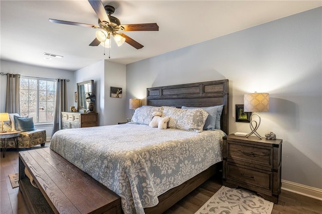 bedroom with a ceiling fan, visible vents, baseboards, and wood finished floors