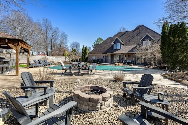 exterior space with an outdoor fire pit, fence, and a community pool