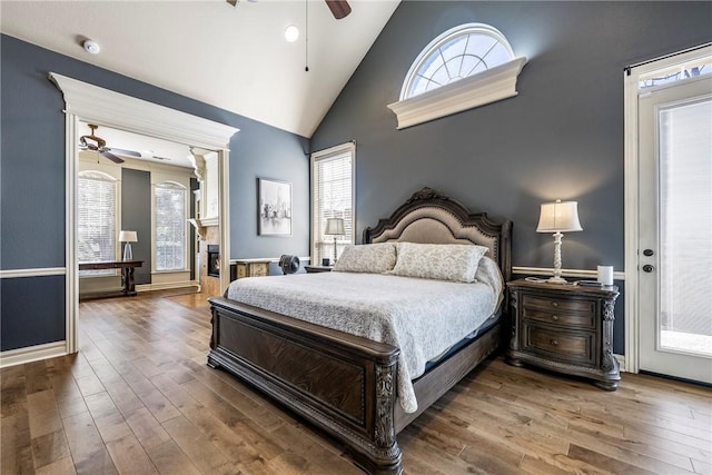 bedroom featuring a ceiling fan, baseboards, high vaulted ceiling, and wood finished floors