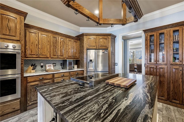 kitchen with appliances with stainless steel finishes, backsplash, light wood-style flooring, and crown molding