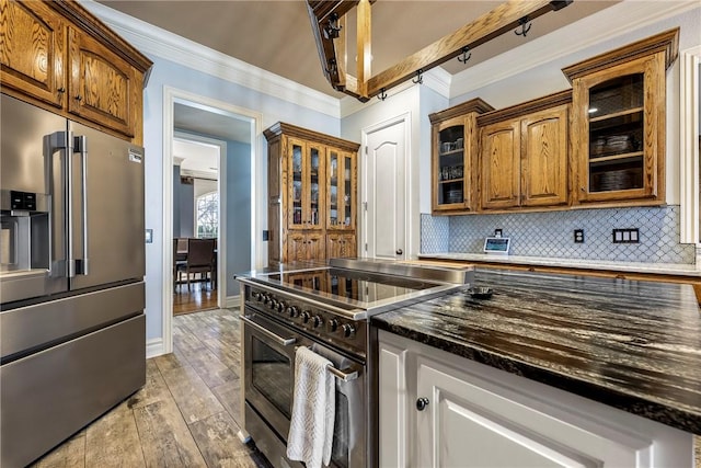 kitchen with light wood-type flooring, decorative backsplash, high end appliances, glass insert cabinets, and crown molding