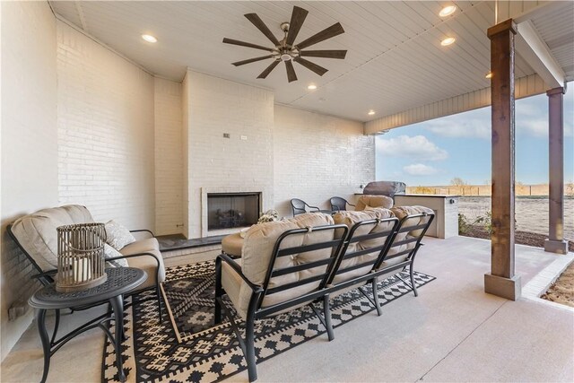 view of patio / terrace with a ceiling fan, outdoor dining area, and an outdoor living space with a fireplace