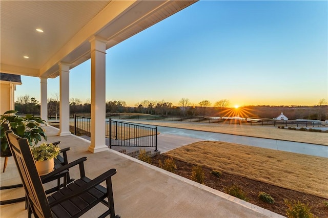 pool at dusk with a patio area and fence