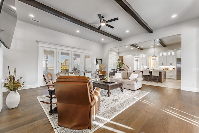 living room with french doors, hardwood / wood-style floors, beam ceiling, and baseboards