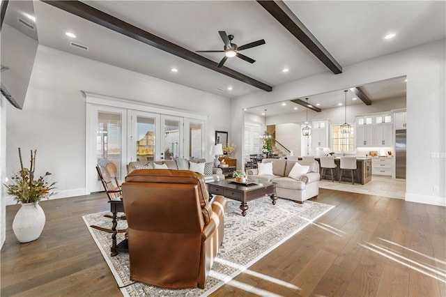 living area featuring beamed ceiling, a ceiling fan, hardwood / wood-style floors, recessed lighting, and stairway