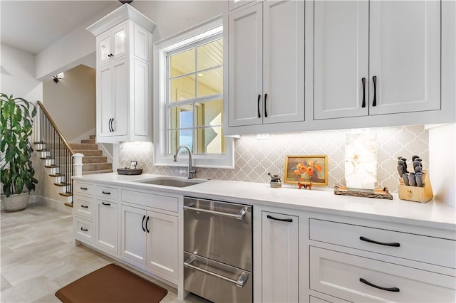 kitchen featuring a sink, white cabinetry, light countertops, a warming drawer, and tasteful backsplash