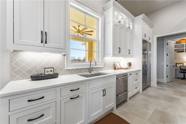 kitchen with a sink, white cabinetry, backsplash, a warming drawer, and glass insert cabinets