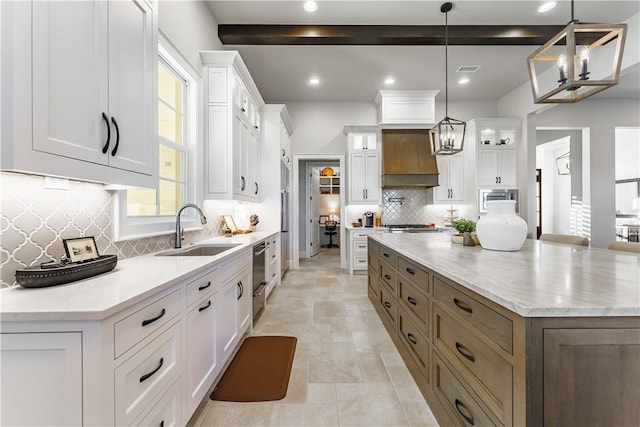 kitchen with a sink, a chandelier, a spacious island, stainless steel microwave, and white cabinets