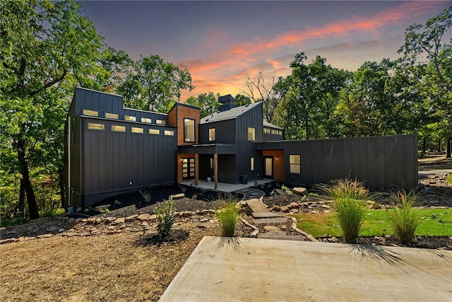 back of house at dusk featuring board and batten siding and a patio area