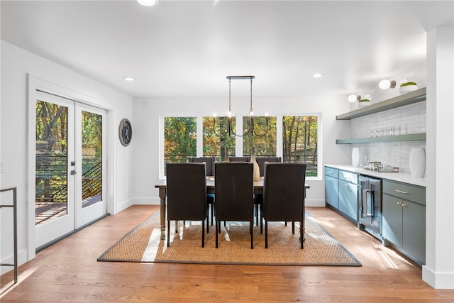 dining room with french doors, a notable chandelier, light wood-type flooring, beverage cooler, and baseboards