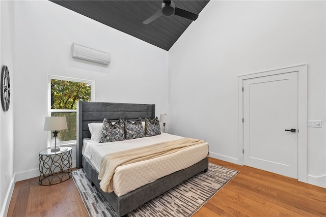 bedroom with an AC wall unit, wood finished floors, and baseboards