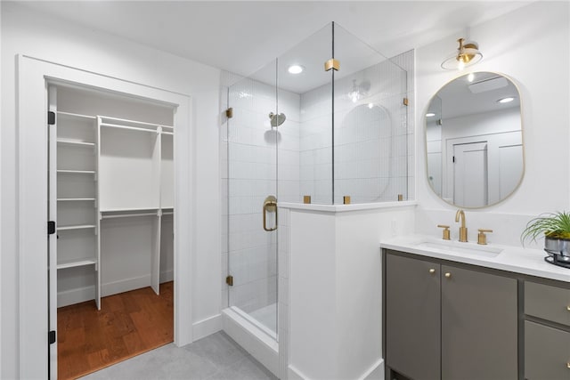 bathroom with a walk in closet, a shower stall, vanity, and recessed lighting