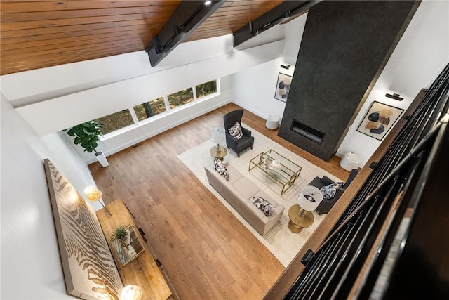 living room featuring beam ceiling, a fireplace, a barn door, wood ceiling, and wood finished floors