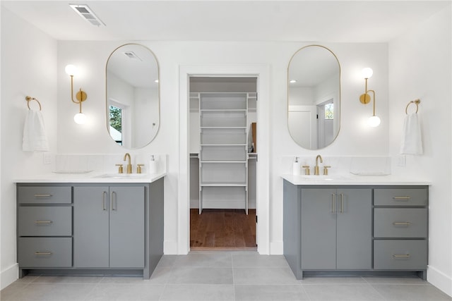 full bathroom with two vanities, tile patterned flooring, visible vents, and a sink