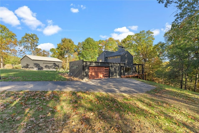 view of front of house with a garage, a front yard, an outdoor structure, and an outbuilding