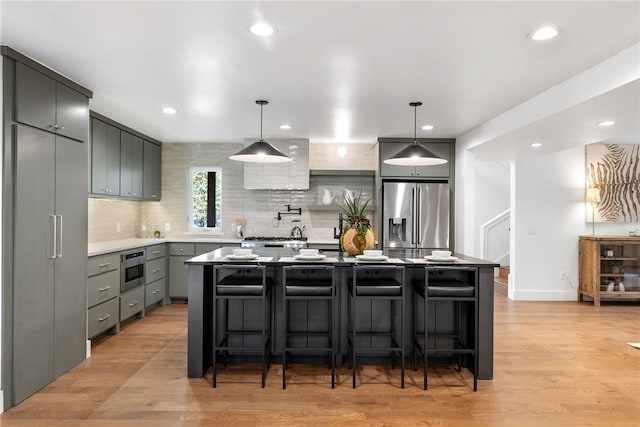 kitchen featuring appliances with stainless steel finishes, light wood-type flooring, gray cabinets, and decorative backsplash