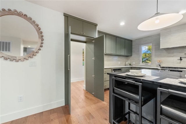 kitchen with visible vents, baseboards, light countertops, light wood-type flooring, and decorative backsplash