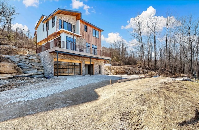 view of front facade featuring an attached garage, stone siding, and driveway