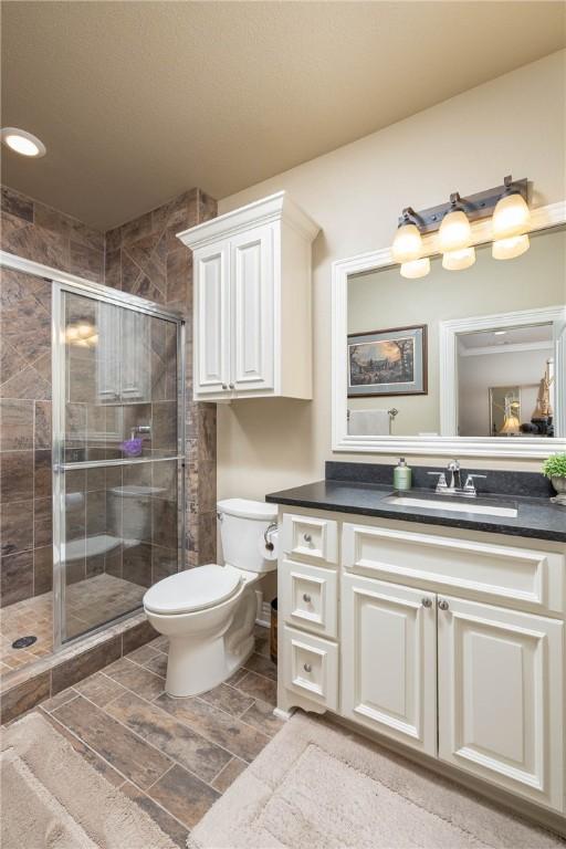 bathroom featuring toilet, a shower stall, and vanity