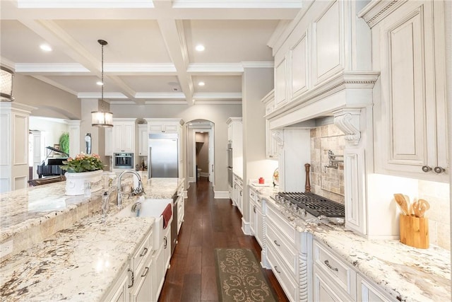 kitchen featuring decorative columns, arched walkways, coffered ceiling, dark wood-style flooring, and built in fridge