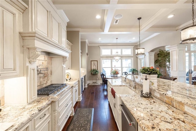 kitchen featuring coffered ceiling, a sink, appliances with stainless steel finishes, dark wood finished floors, and decorative columns