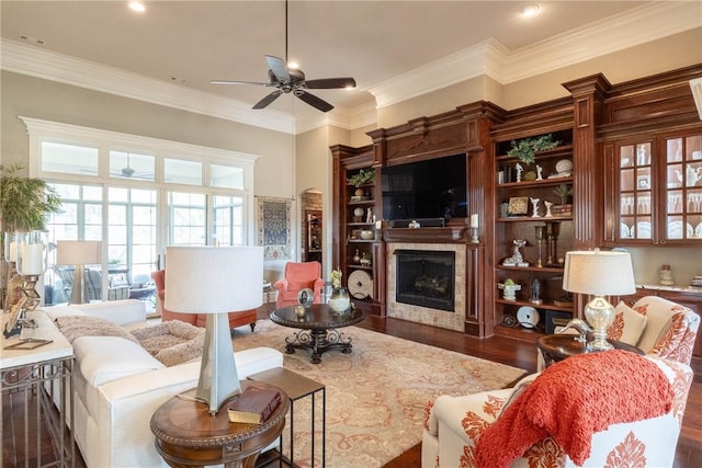 living room featuring ornamental molding, a fireplace, dark wood finished floors, and a ceiling fan