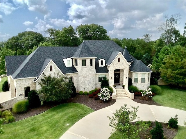 french country home with stone siding, roof with shingles, and a front lawn